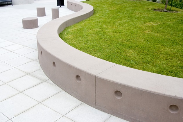 Gently curving concrete retaining wall following the contours of a sloped garden